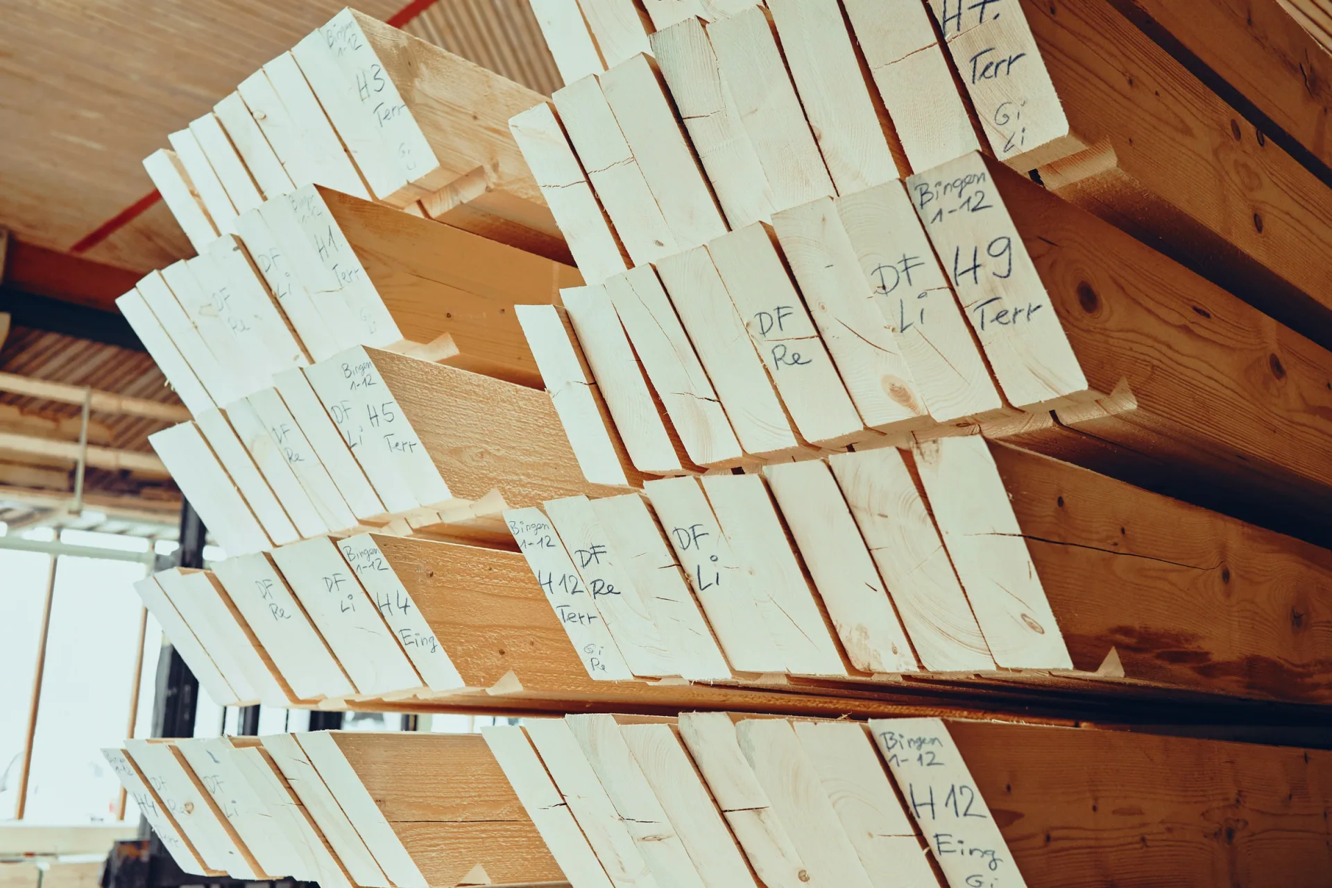 Gestapelte Balken mit handschriftlicher Beschriftung im Holzlager